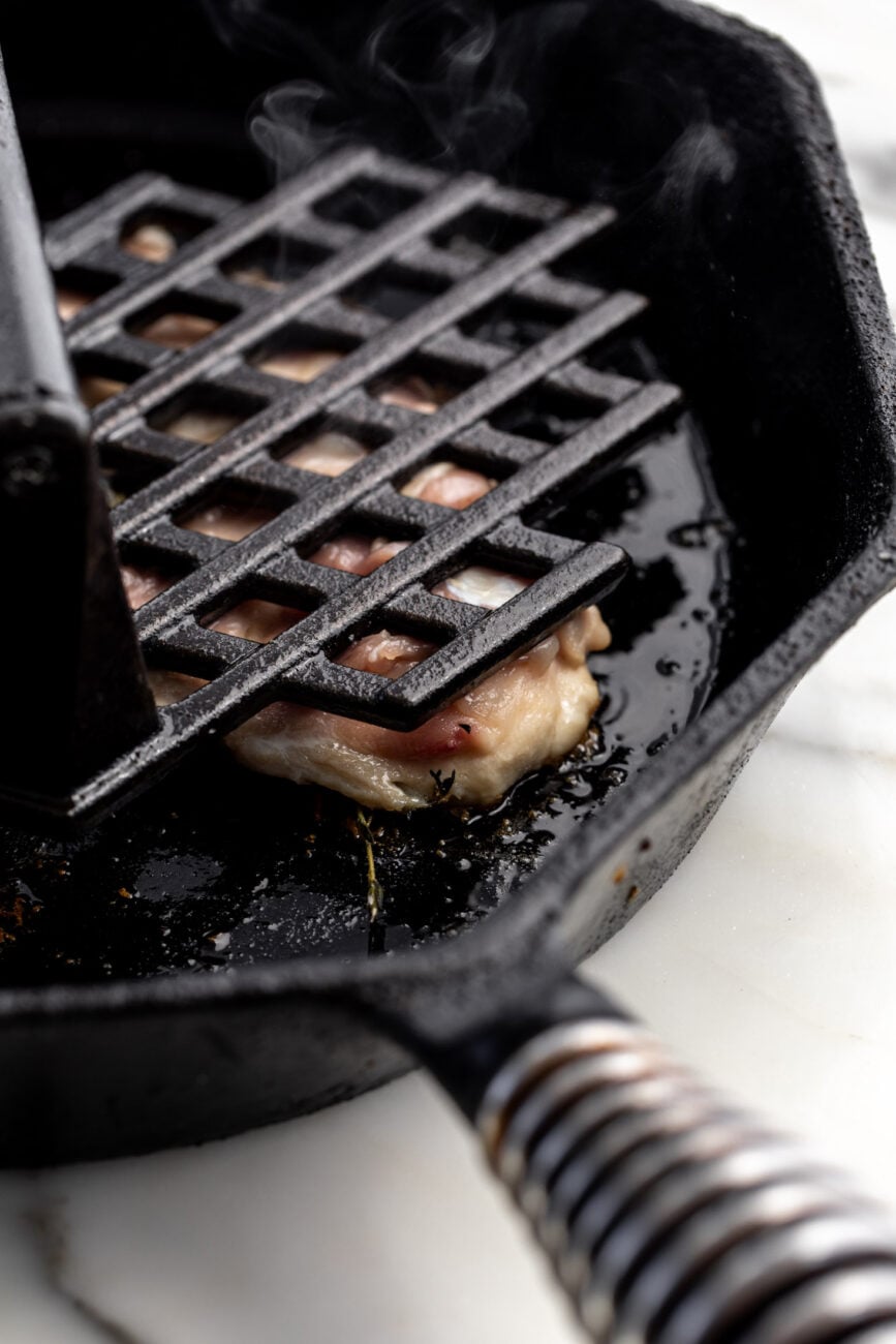 pressed deboned chicken legs in pan with cast iron press.