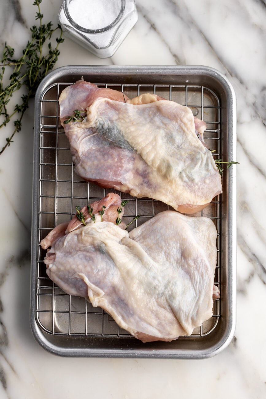 salted skin-on chicken legs with herbs under skin.
