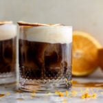 mont blanc iced coffee with orange cold foam and dried orange slice garnish.