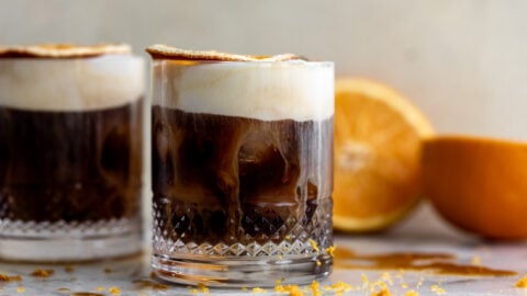 mont blanc iced coffee with orange cold foam and dried orange slice garnish.