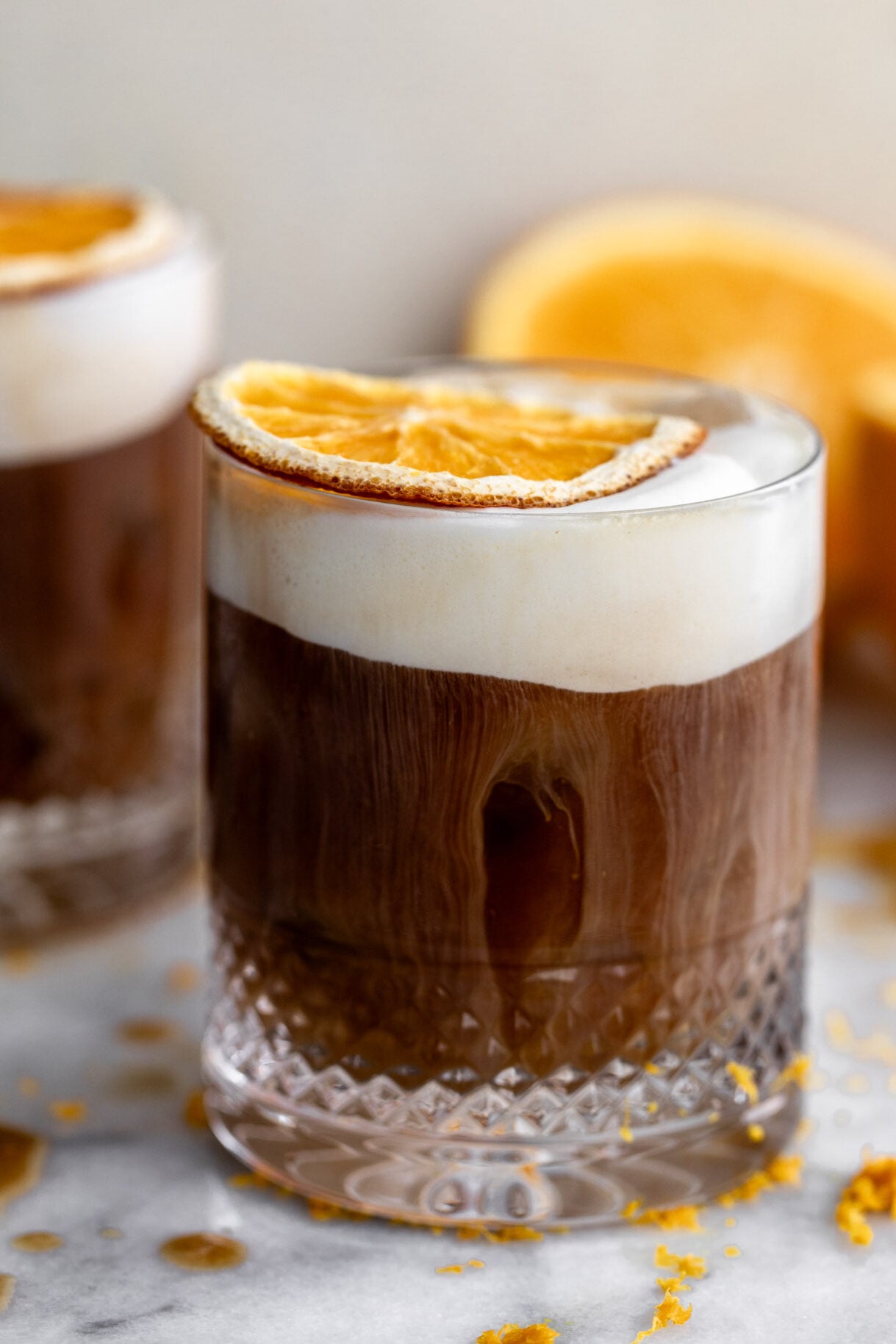 mont blanc iced coffee with orange cold foam and dried orange slice garnish.