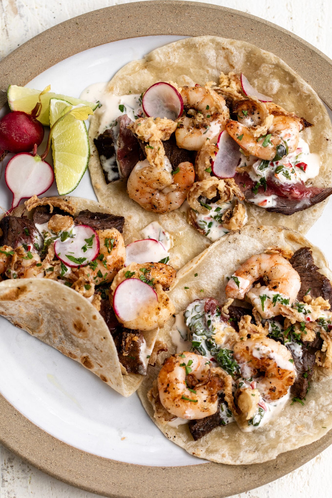 surf and turf tacos with garlic butter shrimp and seared flank steak on flour tortillas.