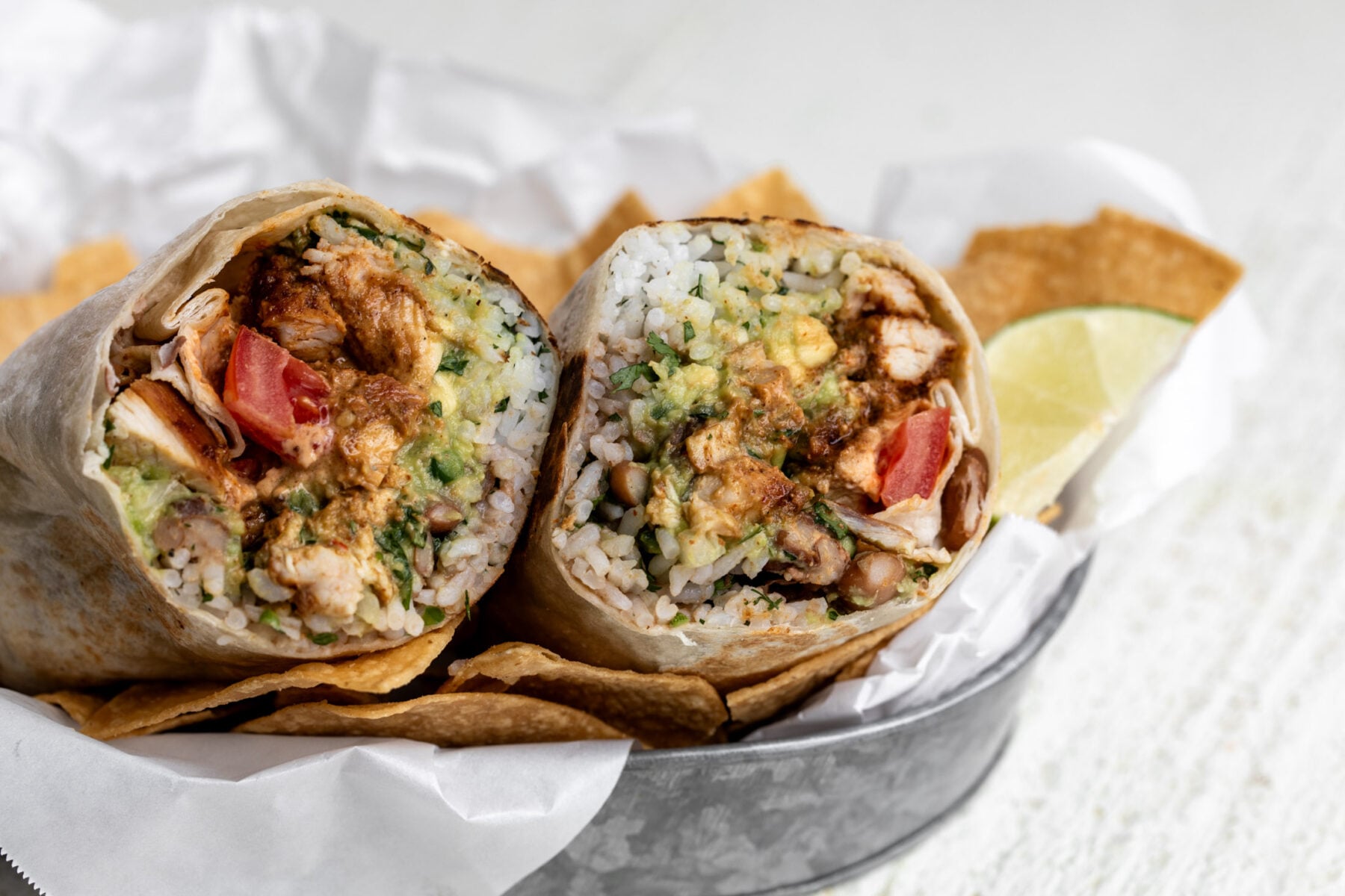 creamy chipotle chicken burrito cut in half with seasoned chicken pinto beans and rice.