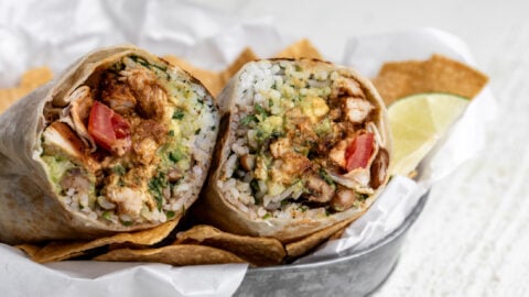 creamy chipotle chicken burrito cut in half with seasoned chicken pinto beans and rice.
