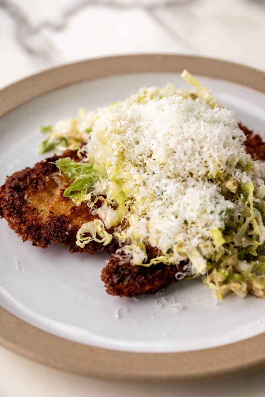 crispy chicken cutlets topped with caesar salad and parmesan cheese. 