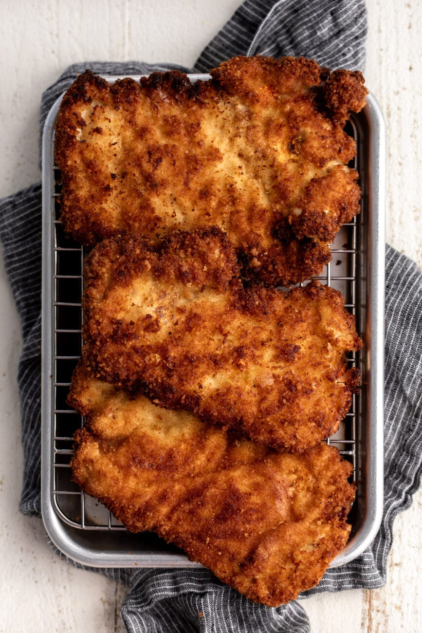 crispy chicken cutlets on wire cooling rack over baking sheet.
