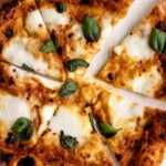 Sungold tomato pizza with mozzarella and basil cut into pieces.
