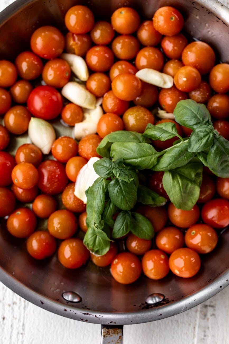 sungold tomatoes with garlic and basil in sauté pan.