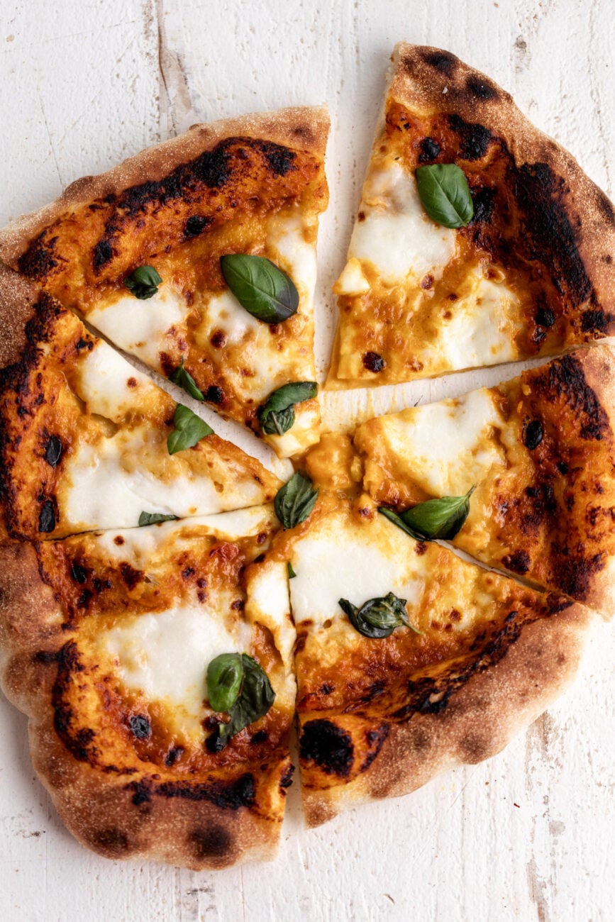 Sungold tomato pizza with mozzarella and fresh basil leaves.
