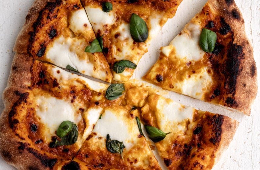 Sungold tomato pizza with mozzarella and basil cut into pieces.
